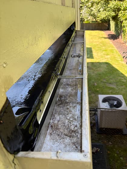The same gutter cleared along its whole length, the air-conditioning unit below it for reference.