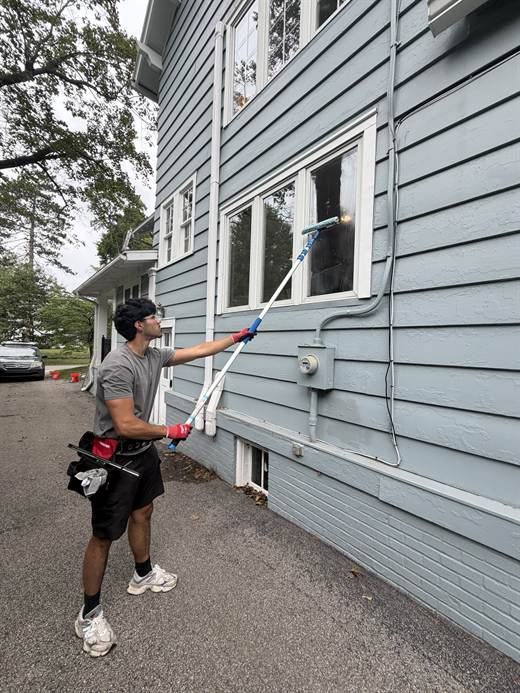 One of us washing a window from the driveway of a house in the village.
